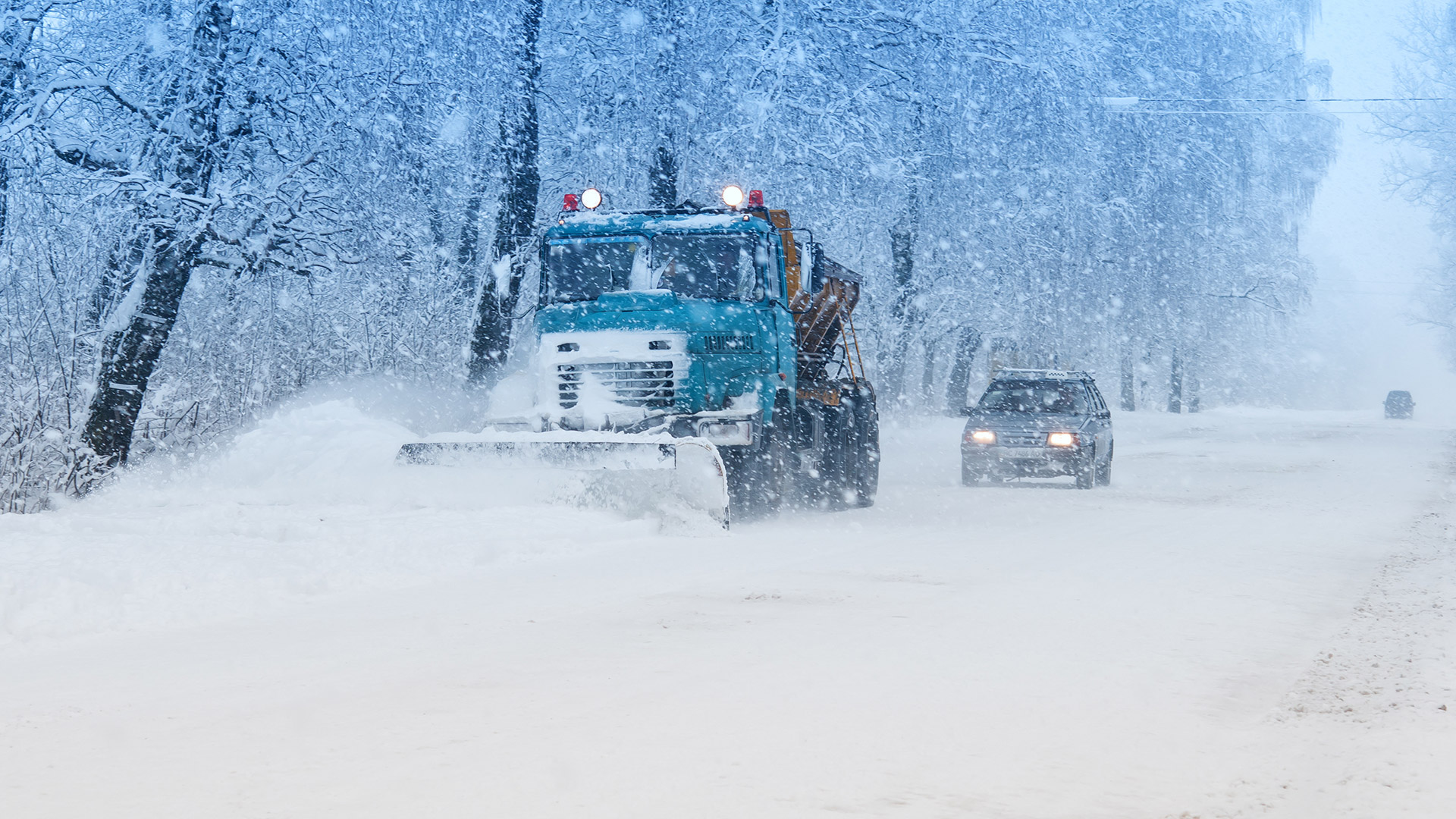 Snowplow and car in winter blizzard.