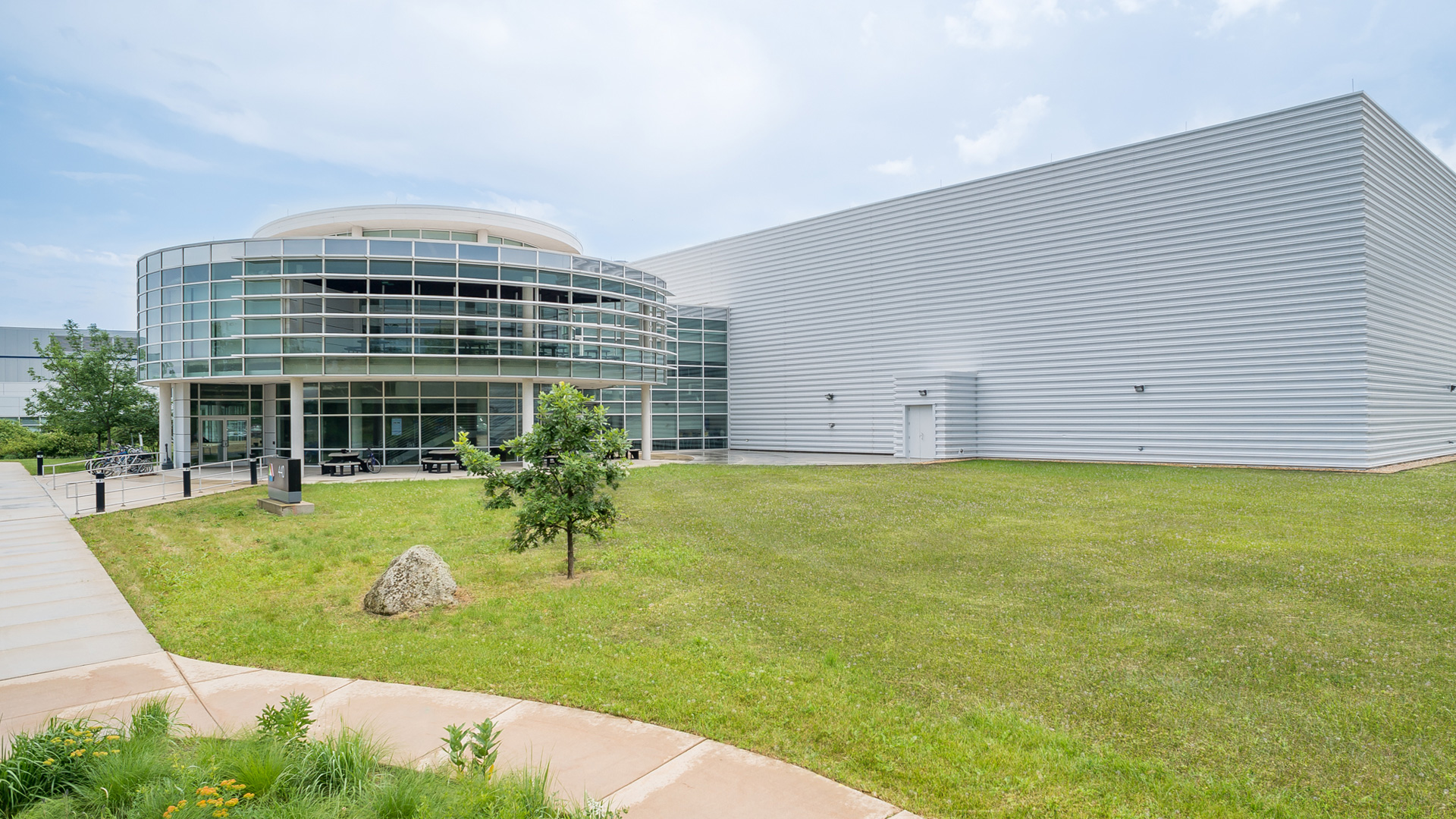 Exterior of CNM Building. Left part is round and glass-covered, and joined to a white windowless rectangular part.