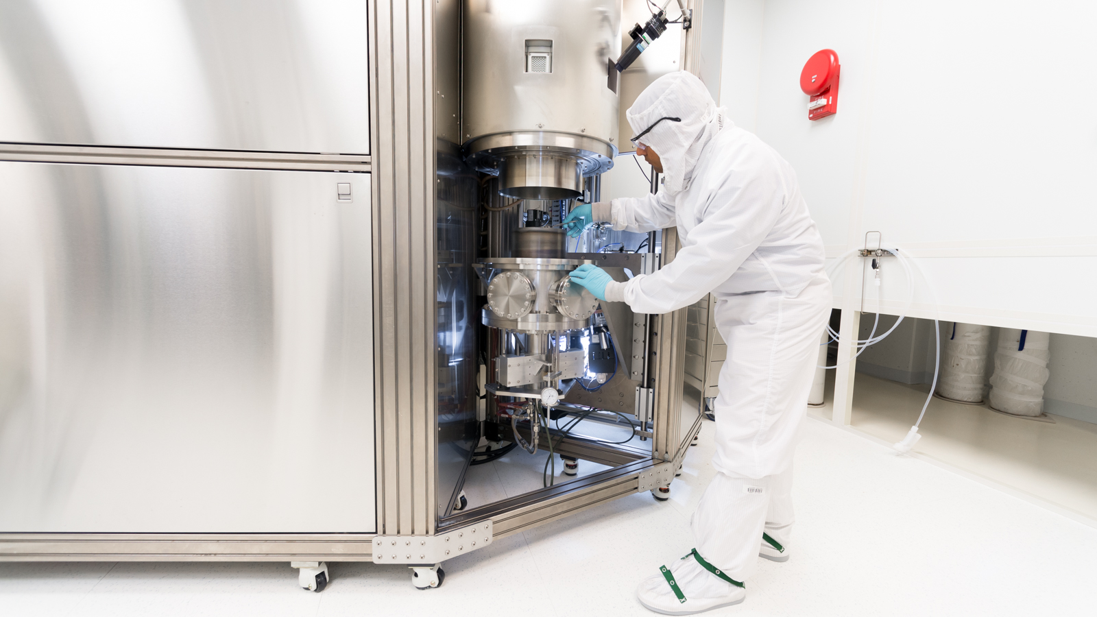 Person in clean suit adjusting metal equipment