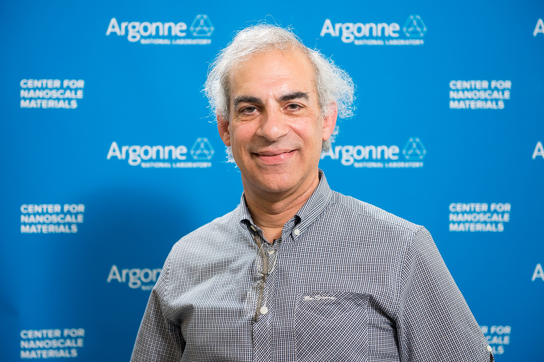 Smiling man in front of Blue Argonne logo backdrop.