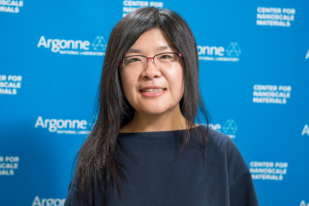 Dark-haired woman wearing glasses, in front of Blue Argonne logo backdrop.