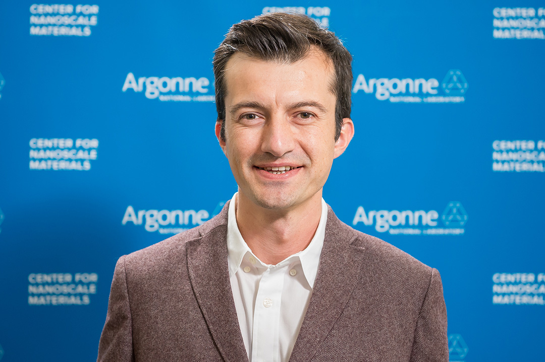 Smiling man in front of Blue Argonne logo backdrop.