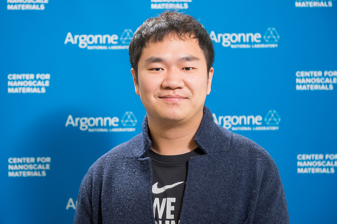 Smiling man in front of Blue Argonne logo backdrop.