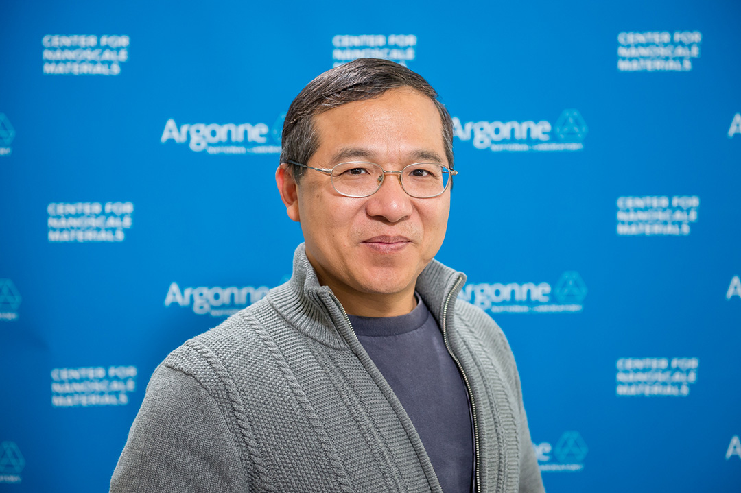 Smiling man wearing glasses, in front of Blue Argonne logo backdrop.