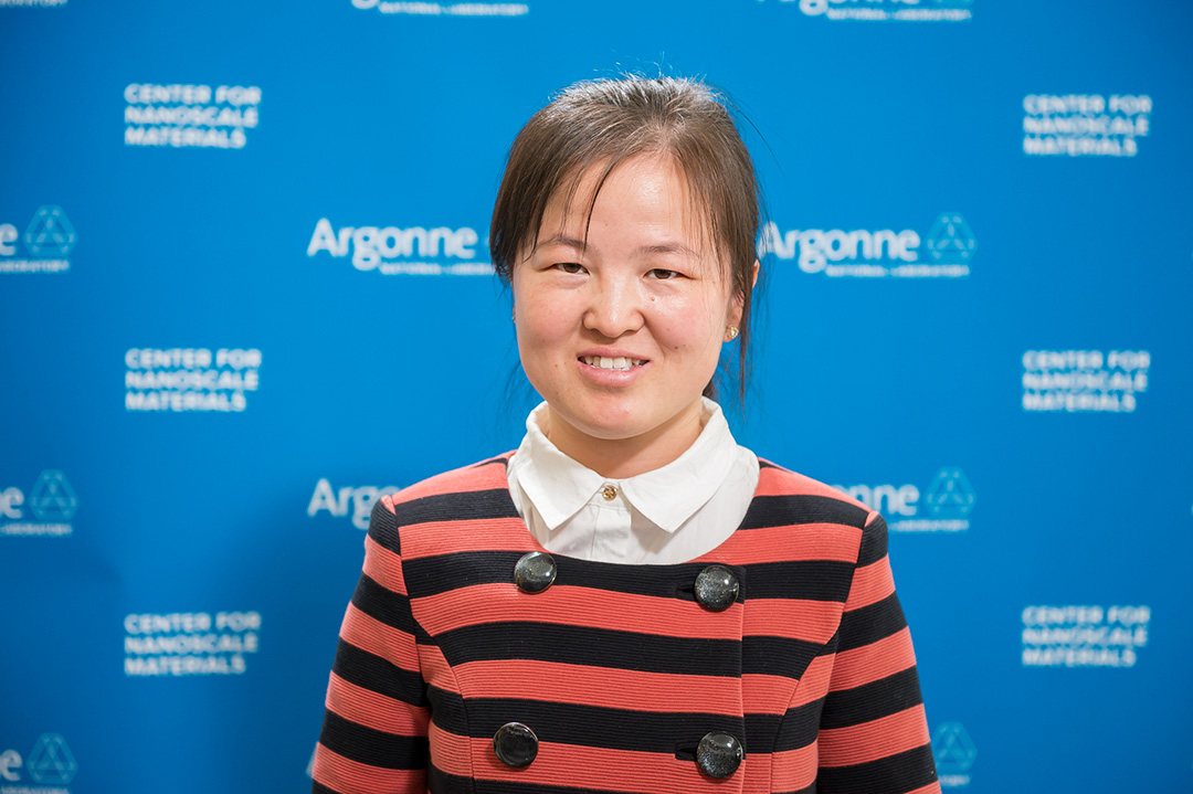 Smiling woman in front of Blue Argonne logo backdrop.