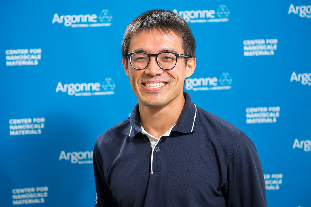 Smiling man wearing glasses, in front of Blue Argonne logo backdrop.