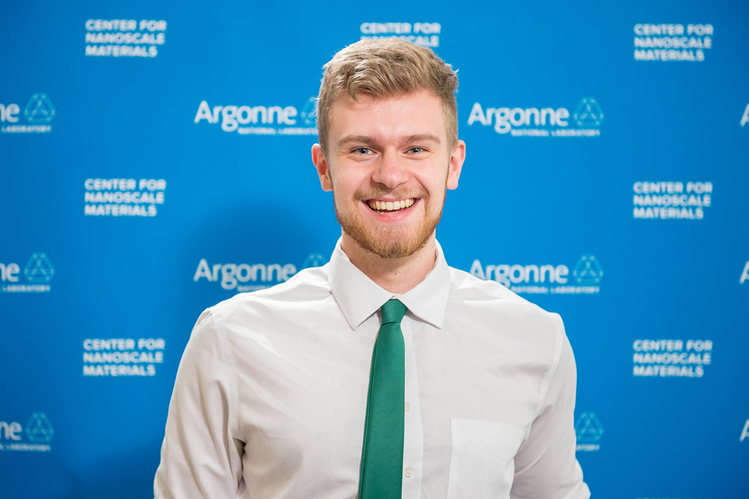 Smiling man in front of Blue Argonne logo backdrop.