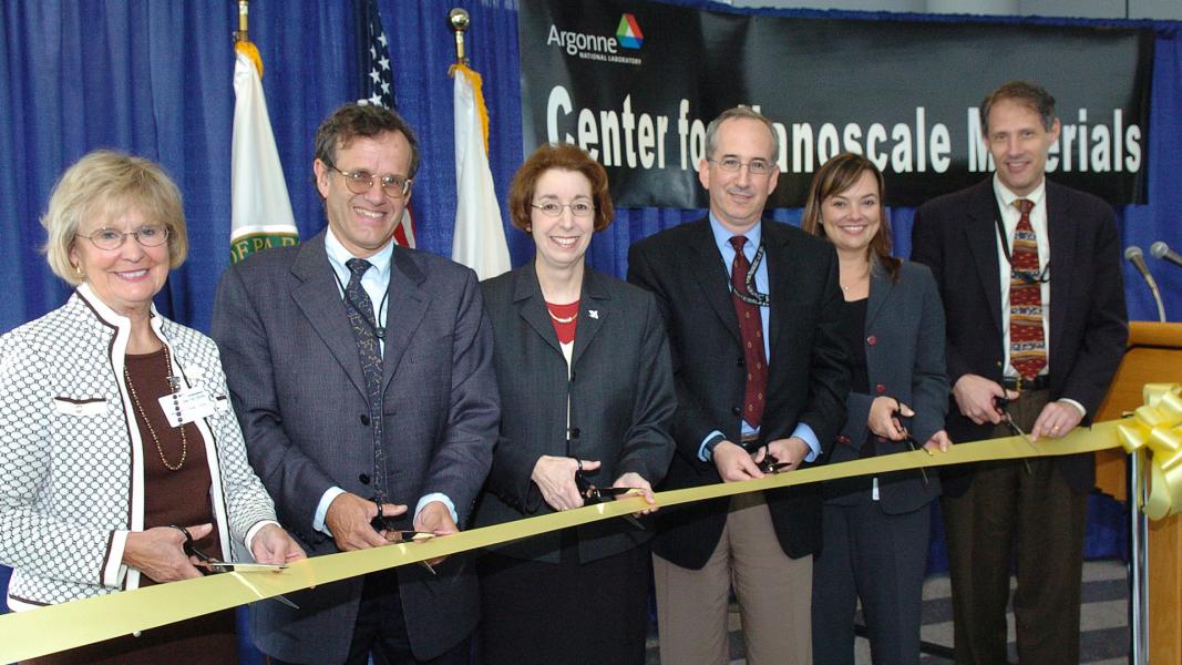 Six people cutting yellow ribbon.