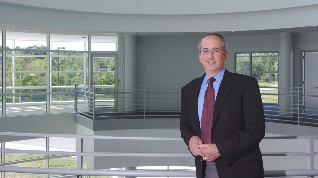 Man leaning on white railing of atrium balcony.