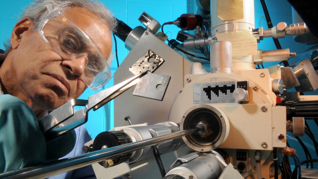 Closeup of man in safety goggles holding chips with large tweezers.