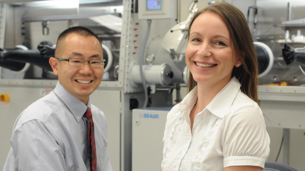 Man and woman smiling at camera in front of equipment.