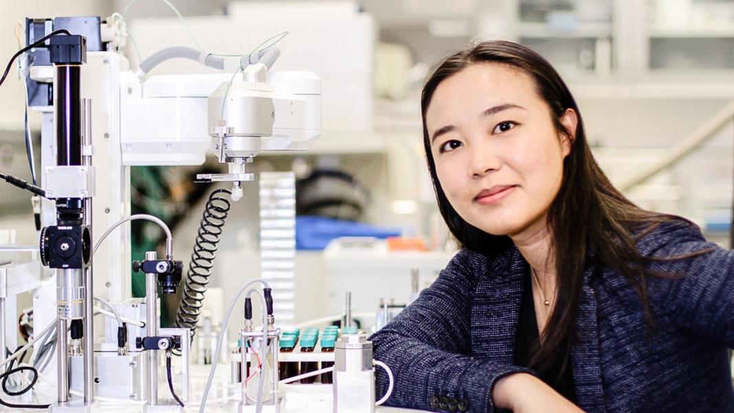 Woman seated at lab desk smiling at camera.